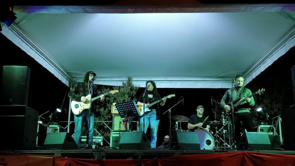greg con la chitarra, bianca con la chitarra, simon con il basso e leo alla batteria tutti sul palco, con meno luci